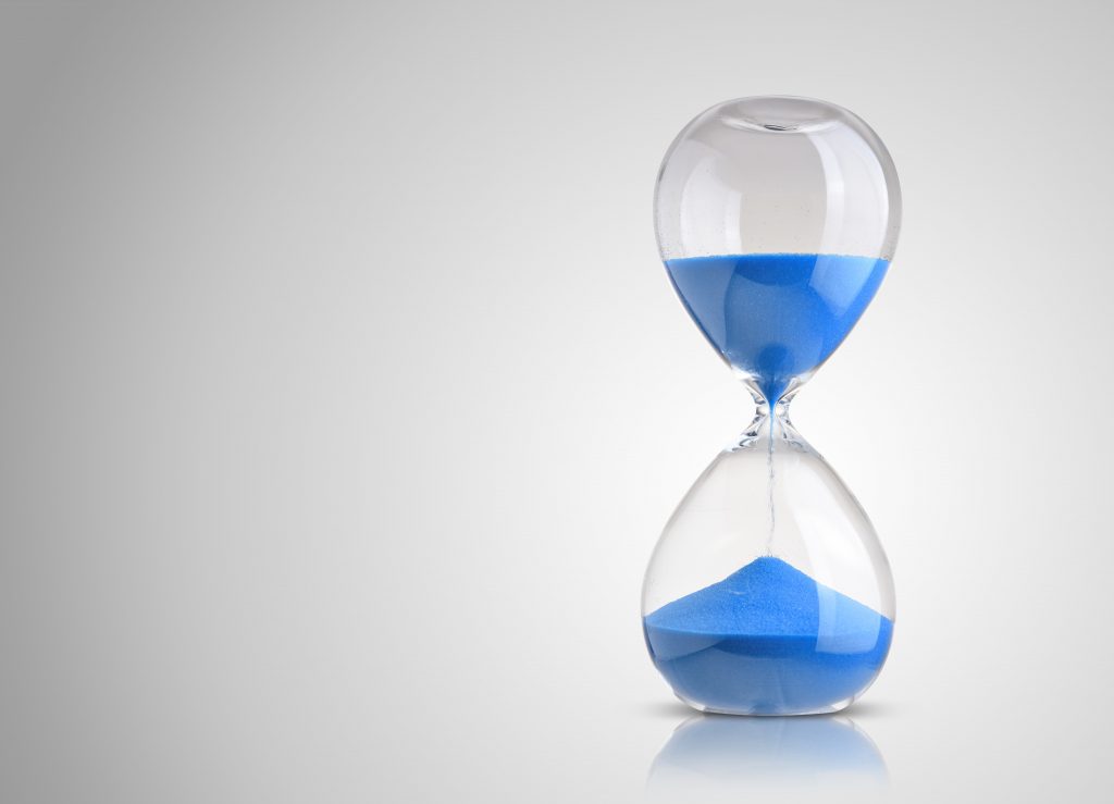 Hour Glass with Blue Sand On Grey Background