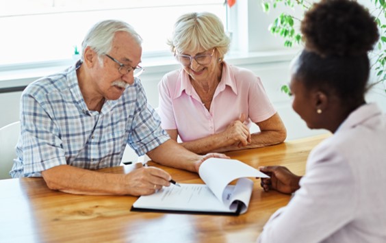 elderly couple signing documents with agent