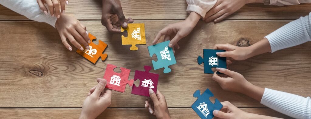 hands holding puzzle pieces with house images on them