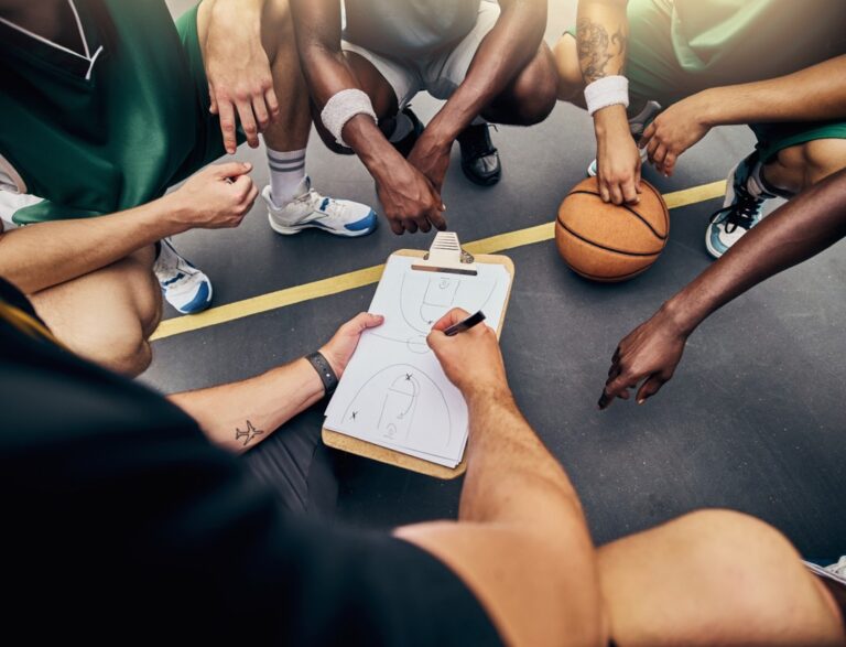 Coach with clipboard and basketball players